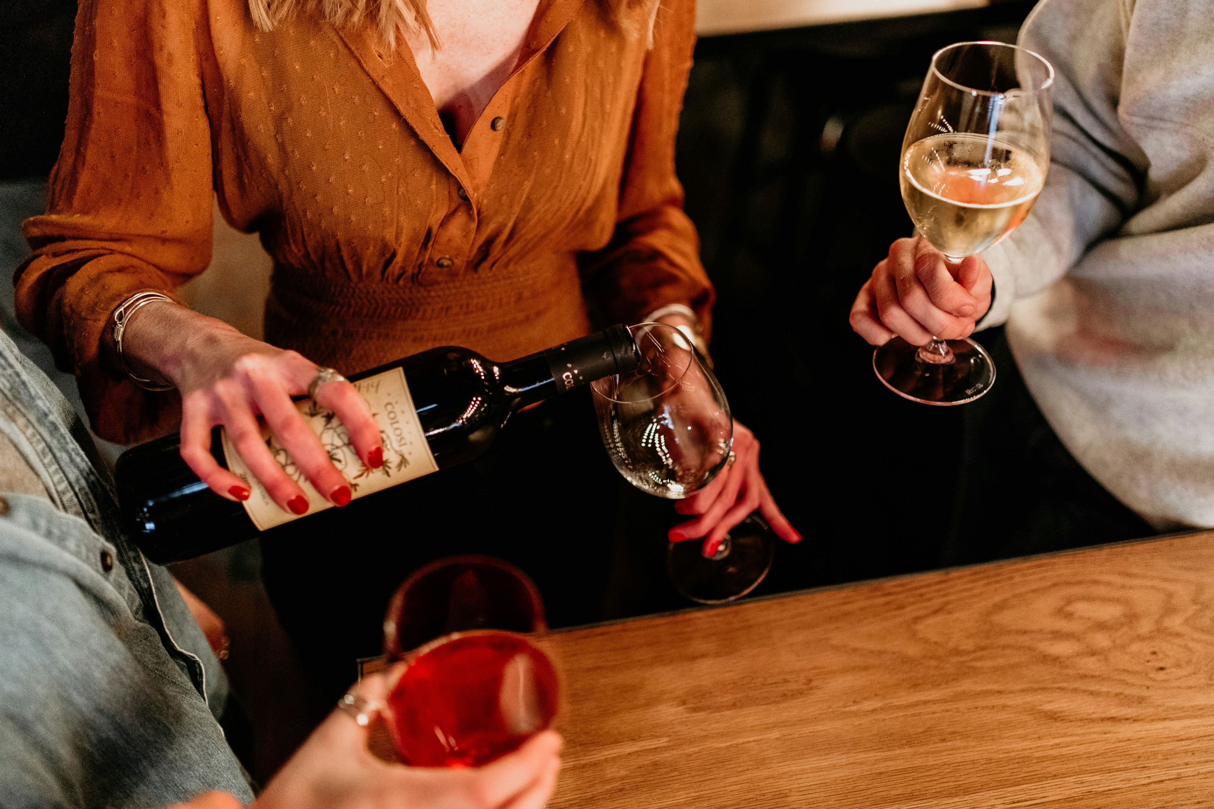 a woman pouring a glass of wine into another woman's hand